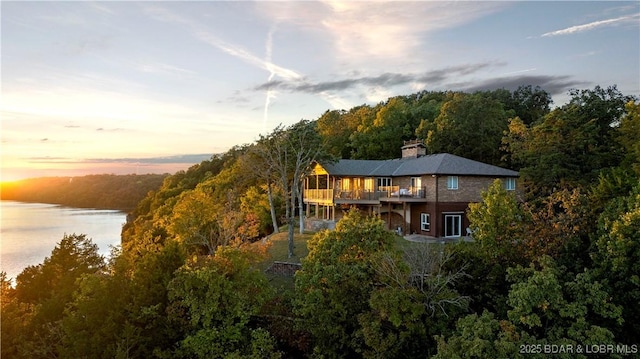 aerial view at dusk with a view of trees and a water view