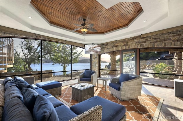 sunroom / solarium with a ceiling fan, a raised ceiling, wood ceiling, and a water view