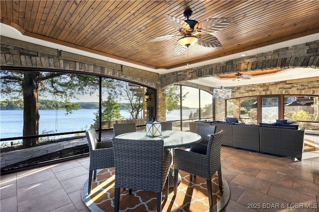 sunroom featuring wood ceiling, a ceiling fan, and a water view