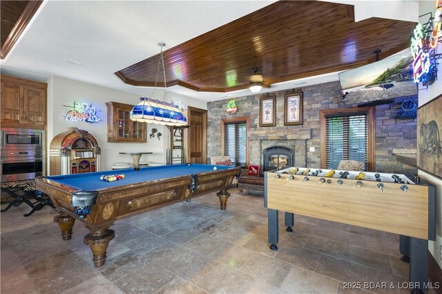game room with a ceiling fan, a tray ceiling, billiards, and a fireplace
