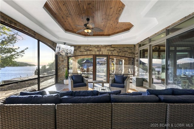 sunroom featuring a tray ceiling, a water view, wood ceiling, and a ceiling fan