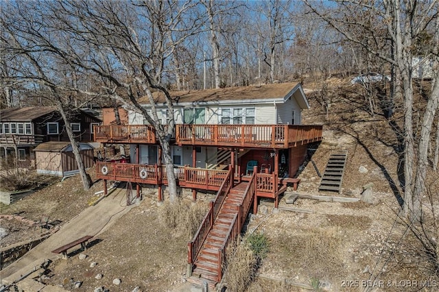 back of property featuring an outbuilding, a storage shed, a deck, and stairs