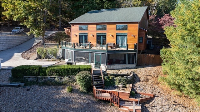 rear view of property with stairs, fence, and a sunroom