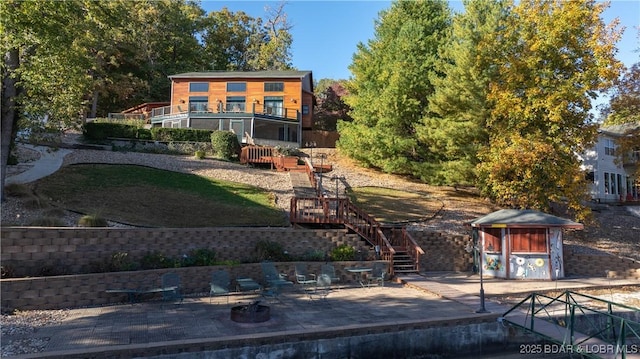 rear view of house featuring stairway, an outbuilding, a patio area, and a shed