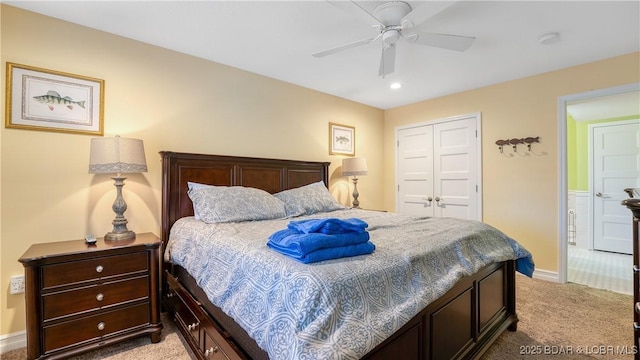 bedroom featuring a closet, light colored carpet, baseboards, and ceiling fan