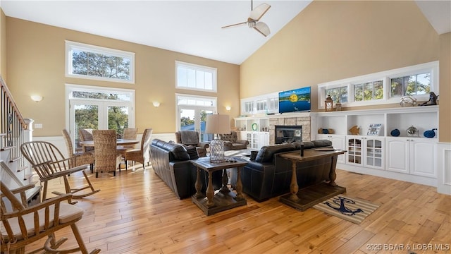 living area with a glass covered fireplace, high vaulted ceiling, and light wood-style floors