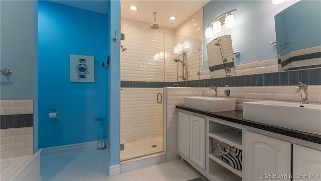 full bathroom featuring a sink, double vanity, a stall shower, and tile patterned floors