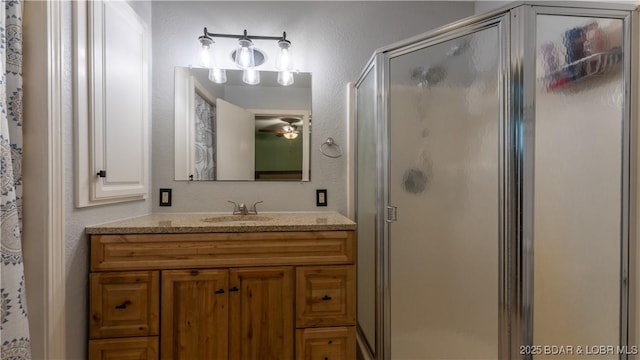 bathroom featuring vanity, a shower stall, a textured wall, and a ceiling fan