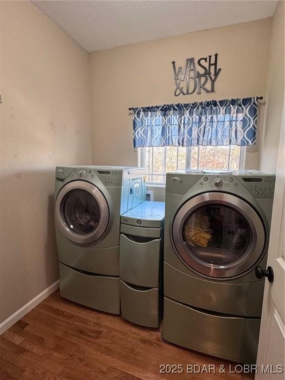 laundry room with wood finished floors, baseboards, laundry area, a textured ceiling, and washer and clothes dryer