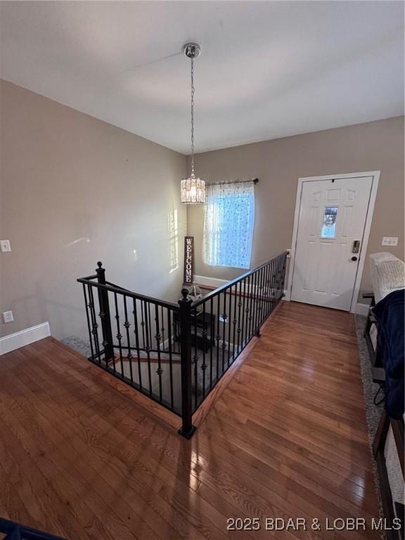 stairs with baseboards, a notable chandelier, and wood finished floors