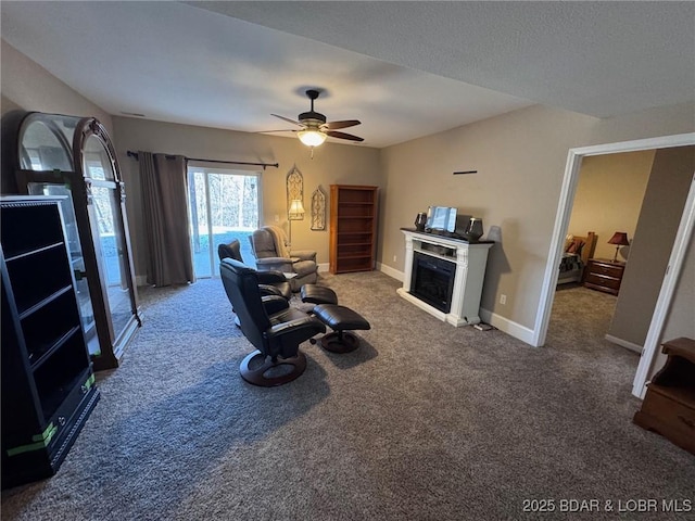 carpeted living area with baseboards, a ceiling fan, and a fireplace