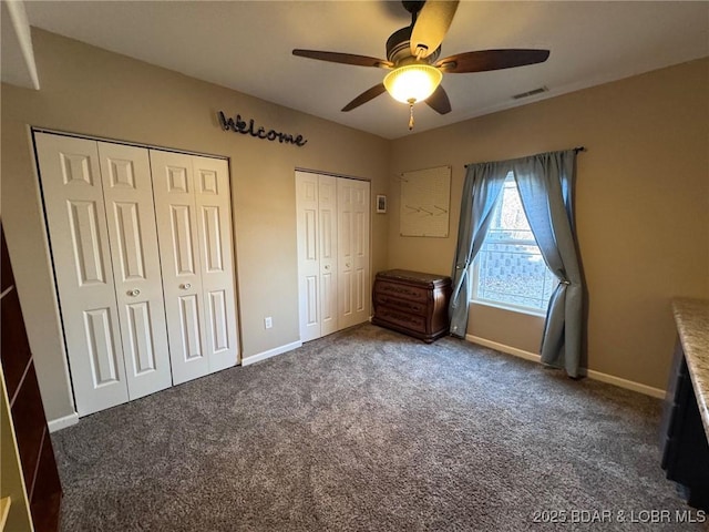 unfurnished bedroom featuring carpet, baseboards, visible vents, and multiple closets