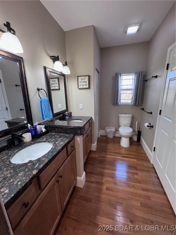 bathroom featuring vanity, toilet, wood finished floors, and baseboards