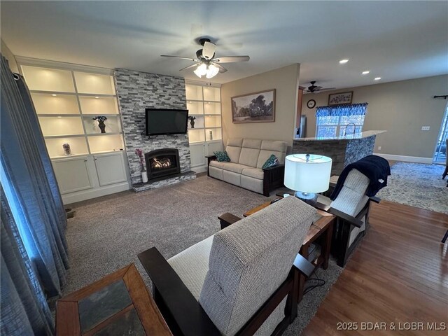 carpeted living area featuring a ceiling fan, wood finished floors, recessed lighting, a fireplace, and baseboards