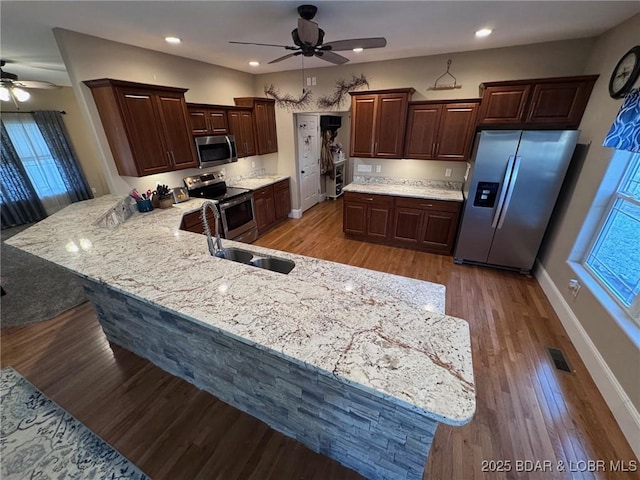 kitchen with a ceiling fan, visible vents, a peninsula, light wood-style floors, and appliances with stainless steel finishes