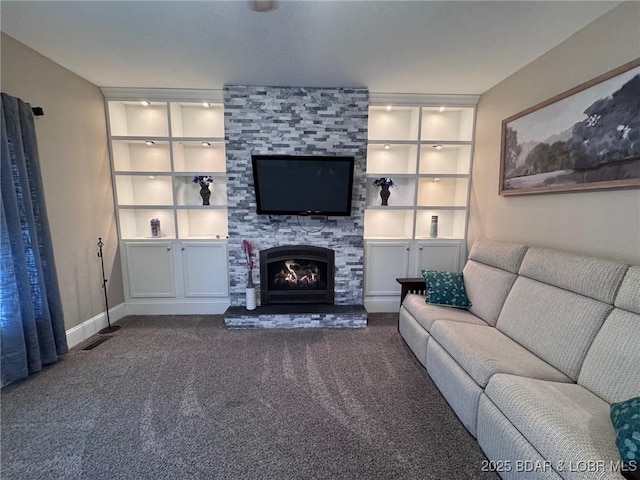 unfurnished living room featuring a stone fireplace, built in features, carpet, and baseboards