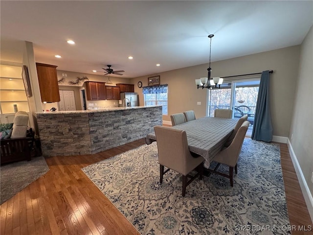 dining room with recessed lighting, ceiling fan with notable chandelier, baseboards, and hardwood / wood-style flooring