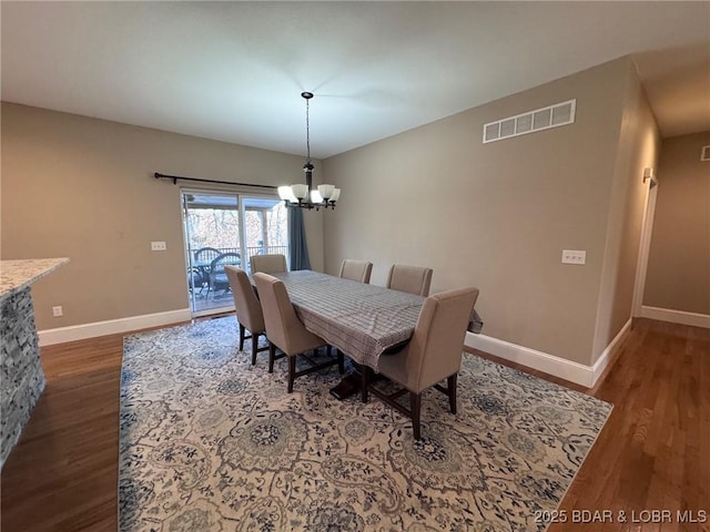 dining area featuring visible vents, baseboards, an inviting chandelier, and wood finished floors