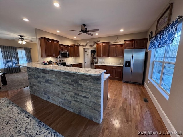 kitchen with wood finished floors, a ceiling fan, and stainless steel appliances