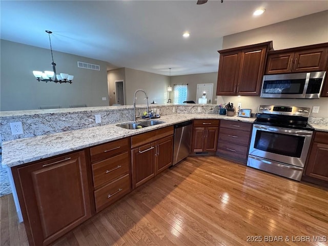 kitchen with visible vents, a chandelier, hardwood / wood-style floors, stainless steel appliances, and a sink