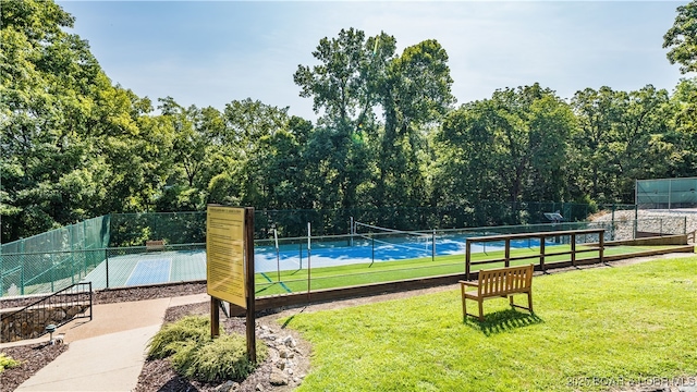 view of property's community with a tennis court, a yard, and fence