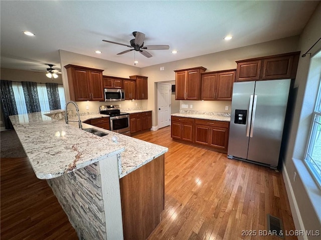 217 Highline Rd, Lake Ozark, MO 65049 - kitchen featuring stainless steel appliances, a ceiling fan, a peninsula, light wood-type flooring, and light stone countertops