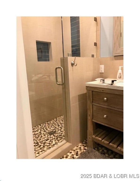 bathroom with tasteful backsplash, a stall shower, and vanity