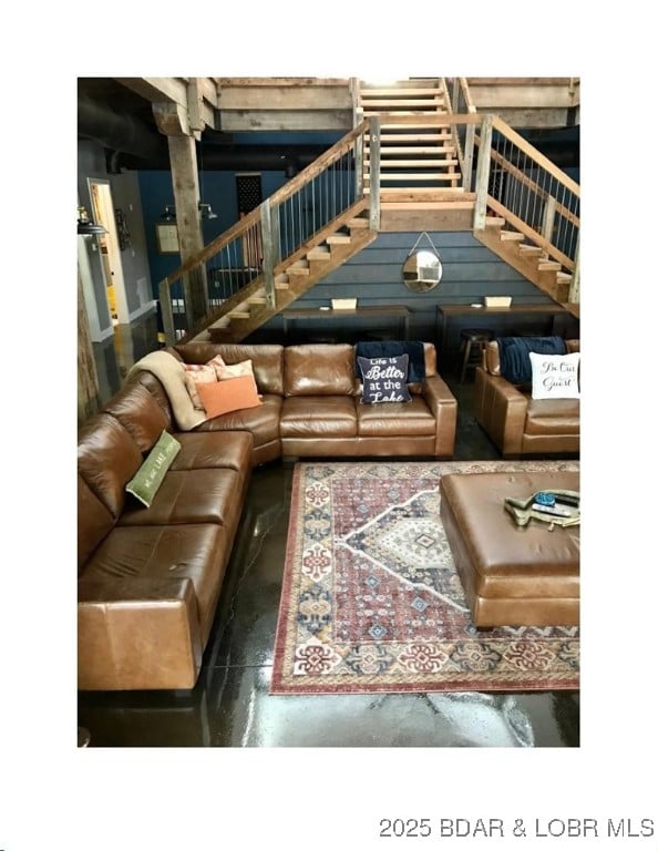 living area featuring concrete flooring and stairs