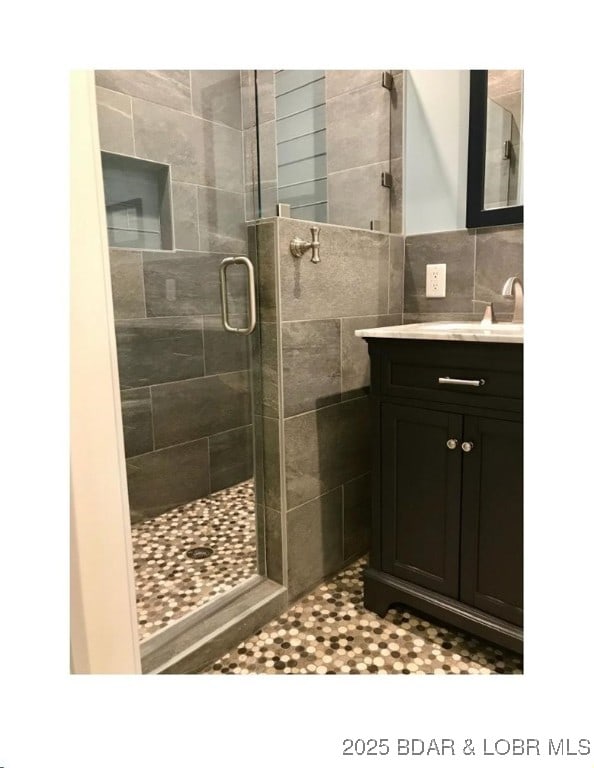 full bathroom featuring tile walls, a stall shower, and vanity