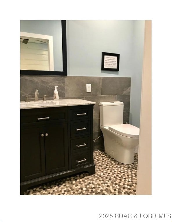 bathroom featuring vanity, tile walls, toilet, and wainscoting