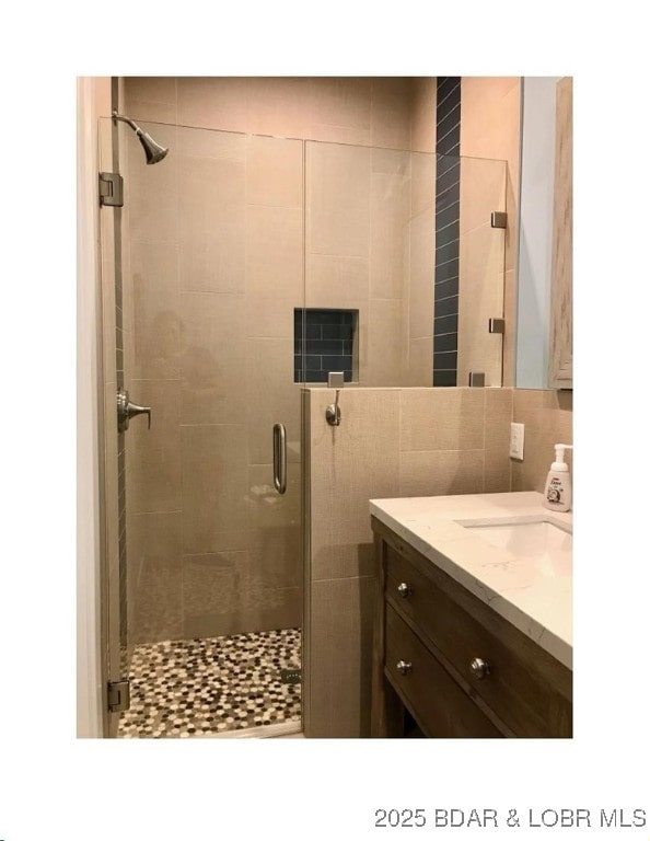 bathroom featuring tasteful backsplash, a shower stall, and vanity