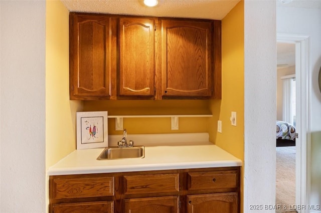 kitchen with brown cabinetry, light countertops, and a sink