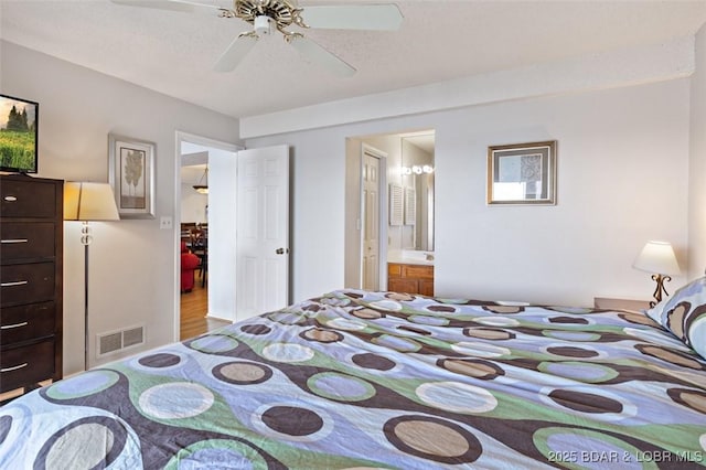 bedroom with ceiling fan, visible vents, wood finished floors, and ensuite bath