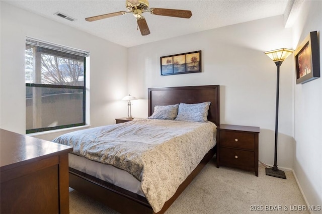 bedroom featuring a textured ceiling, baseboards, visible vents, ceiling fan, and light carpet