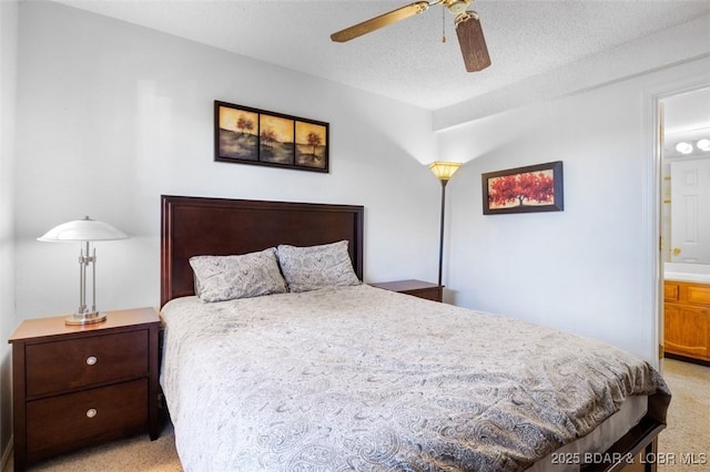 bedroom featuring ceiling fan, light colored carpet, ensuite bathroom, and a textured ceiling