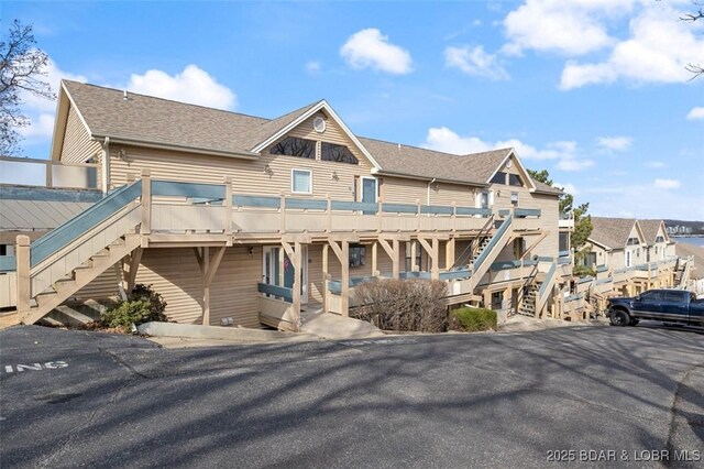 exterior space featuring stairway and roof with shingles