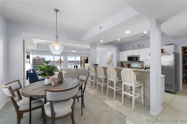 dining room featuring a tray ceiling, light tile patterned floors, and baseboards