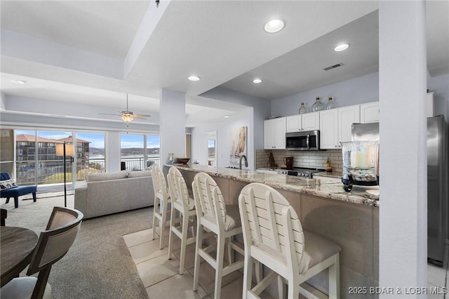372 W Palisades Condo Dr Unit 4A, Lake Ozark, MO 65049 - kitchen with white cabinets, recessed lighting, visible vents, stainless steel microwave, and light stone countertops