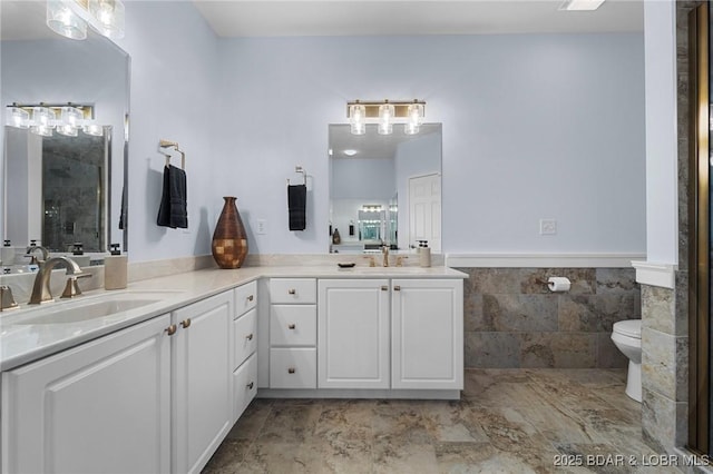 bathroom featuring double vanity, a stall shower, tile walls, and a sink