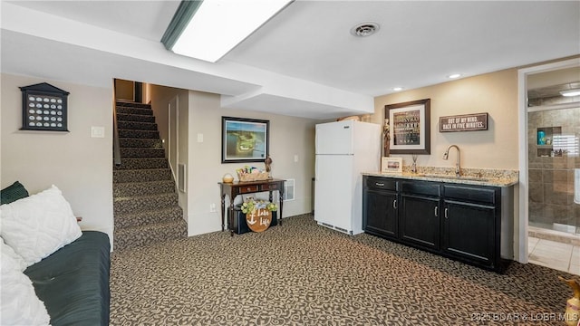 kitchen with visible vents, a sink, freestanding refrigerator, recessed lighting, and dark cabinets