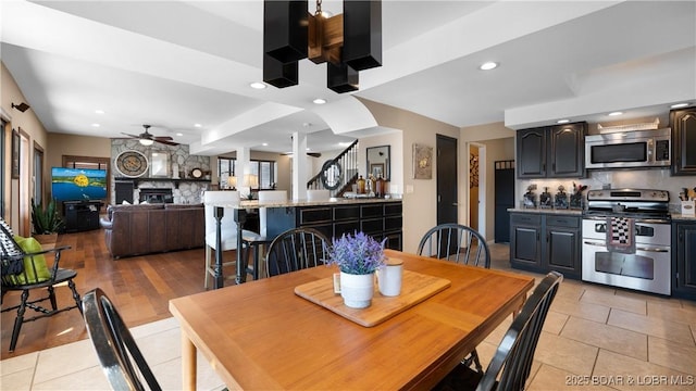 dining room with light tile patterned floors, a ceiling fan, recessed lighting, and a large fireplace