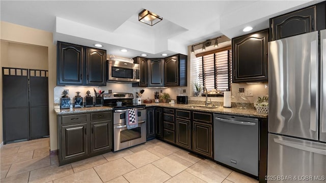 kitchen featuring a sink, recessed lighting, appliances with stainless steel finishes, stone counters, and light tile patterned floors