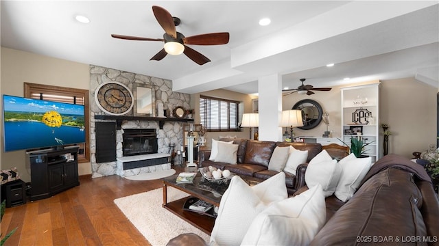 living area with a stone fireplace, recessed lighting, wood finished floors, and ceiling fan