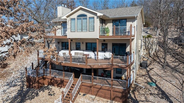 back of property with a balcony, cooling unit, roof with shingles, a chimney, and an outdoor hangout area