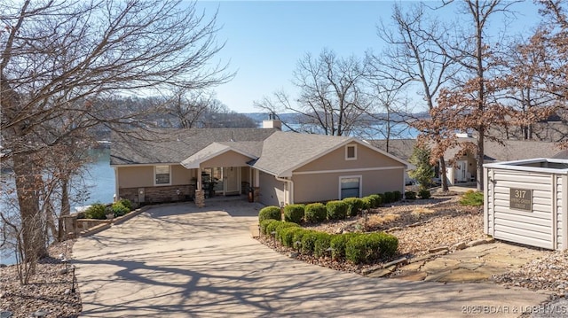 single story home featuring a chimney, stucco siding, concrete driveway, a garage, and stone siding