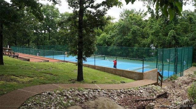 view of tennis court featuring a yard and fence