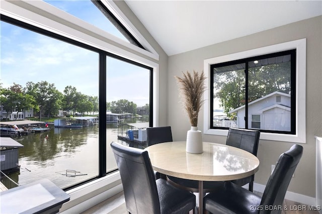 dining room featuring vaulted ceiling, baseboards, and a water view