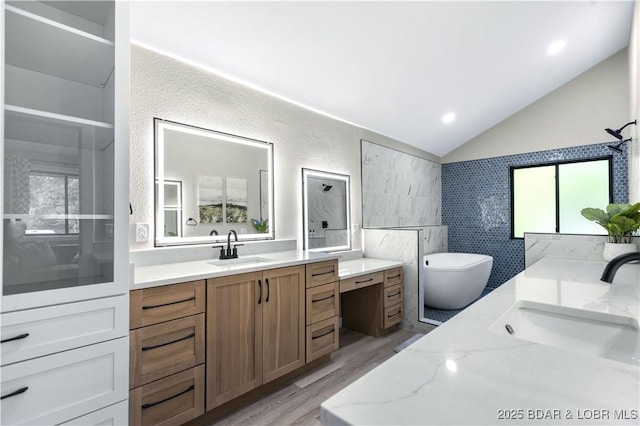 bathroom with a sink, two vanities, a healthy amount of sunlight, and vaulted ceiling