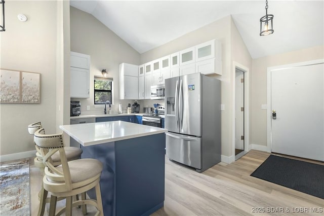 kitchen with a kitchen island, stainless steel appliances, vaulted ceiling, light countertops, and a kitchen bar