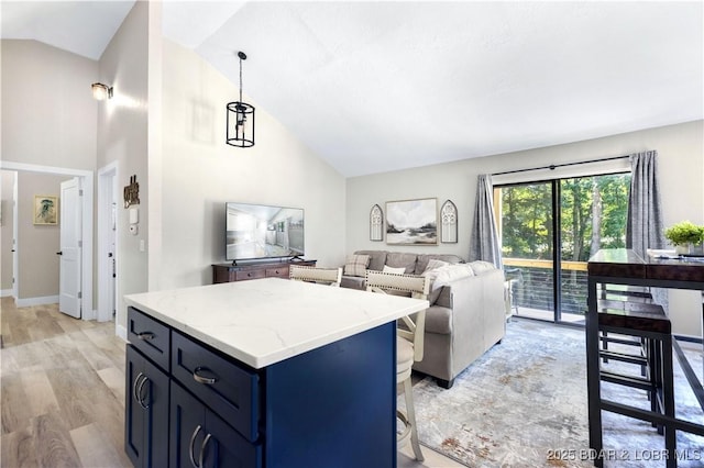 kitchen with light stone countertops, a kitchen island, light wood-style flooring, decorative light fixtures, and blue cabinets